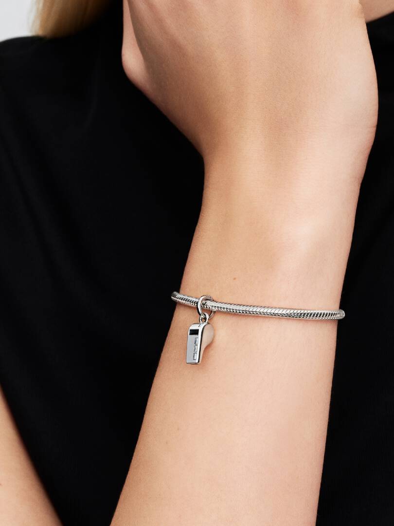 Silver bracelet with a whistle charm on a person's wrist