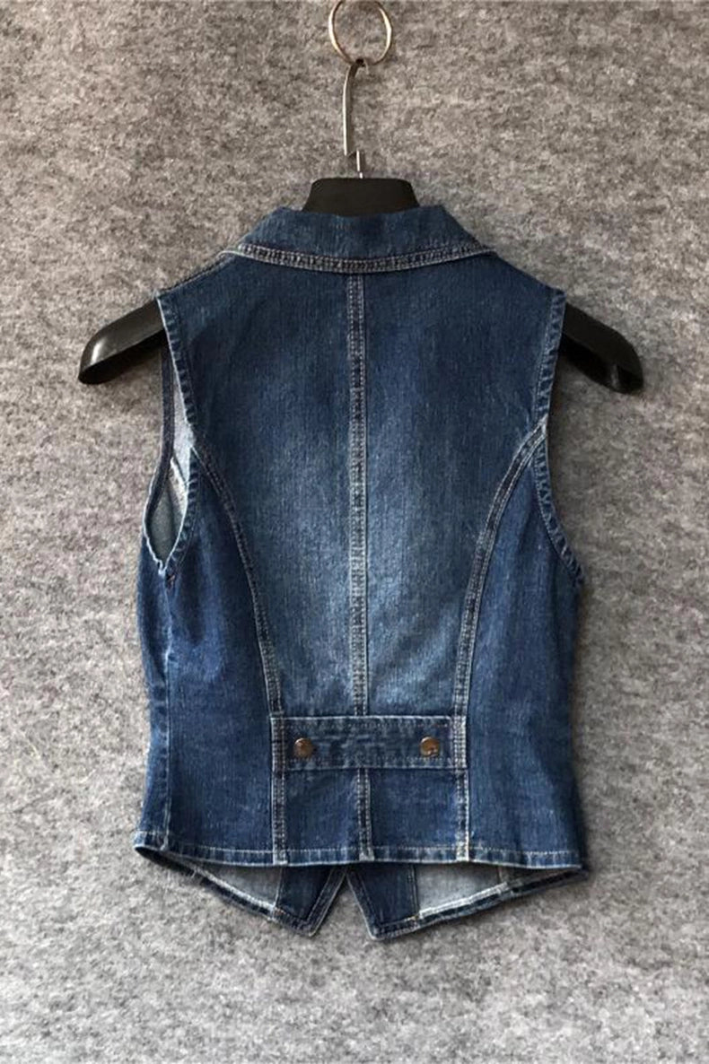 A sleeveless blue denim vest shown from the back, hanging on a black hanger against a textured gray background.
